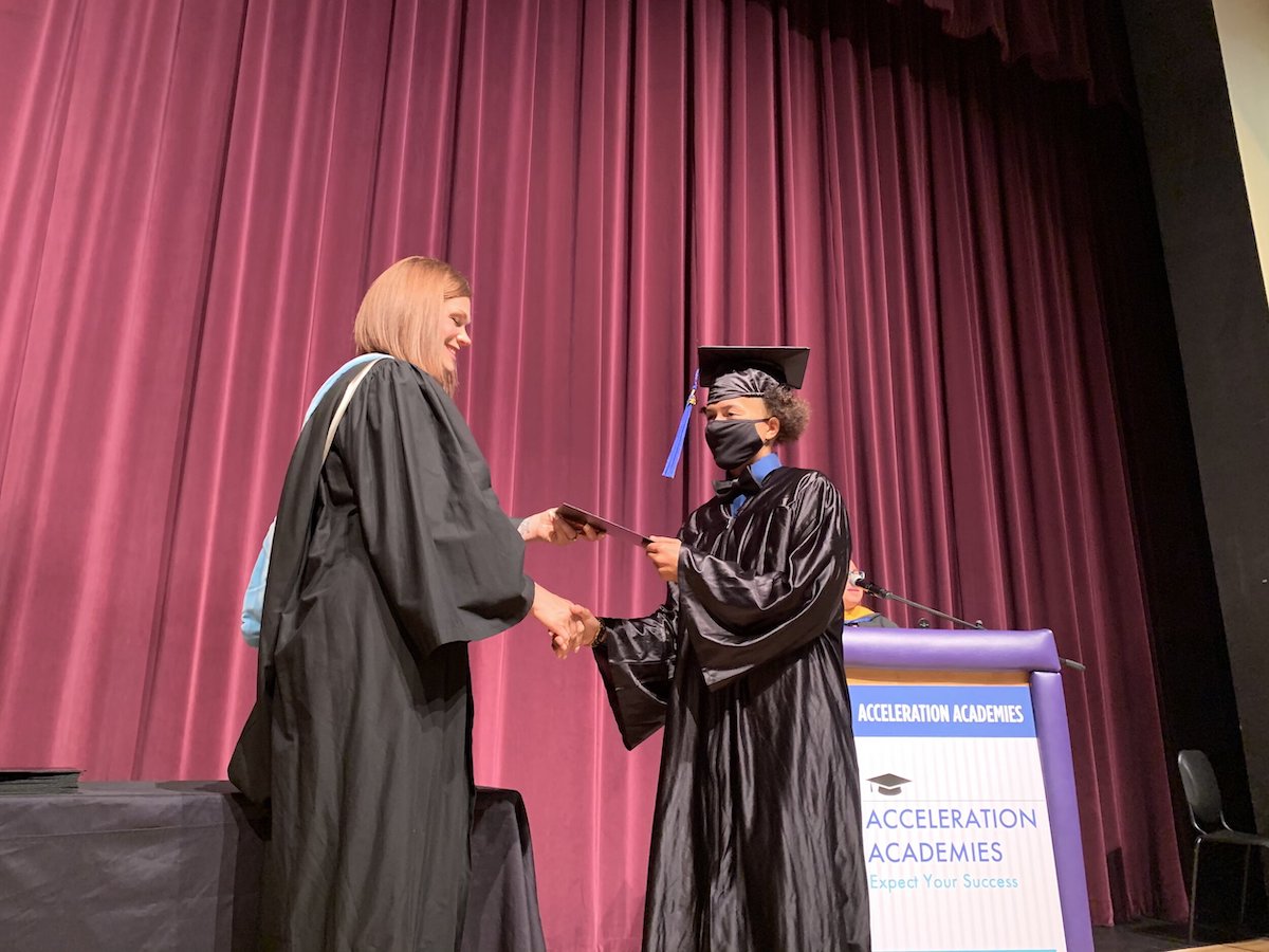 Acceleration Academies graduate shakes hands of director as she celebrates graduation from flexible high school in St. Lucie, Florida